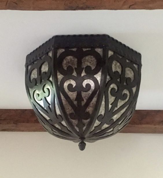 An intricately designed wrought iron light fixture featuring elegant curves and patterns, enhancing any space with its artistic flair.