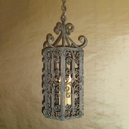 A beautifully crafted wrought iron pendant showcasing intricate scrollwork and a classic design. The fixture features a warm glow from the inner candle, adding elegance to any space.