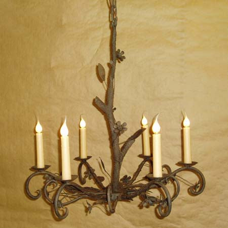 An elegant wrought iron chandelier featuring intricate leaf and flower designs. It has a rustic finish with six candle-like lights, perfect for adding charm and warmth to any space.