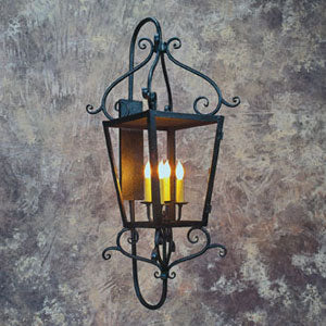 A decorative wrought iron fixture featuring elegant scrollwork and four candle-like bulbs inside a framed glass enclosure, exuding rustic charm.