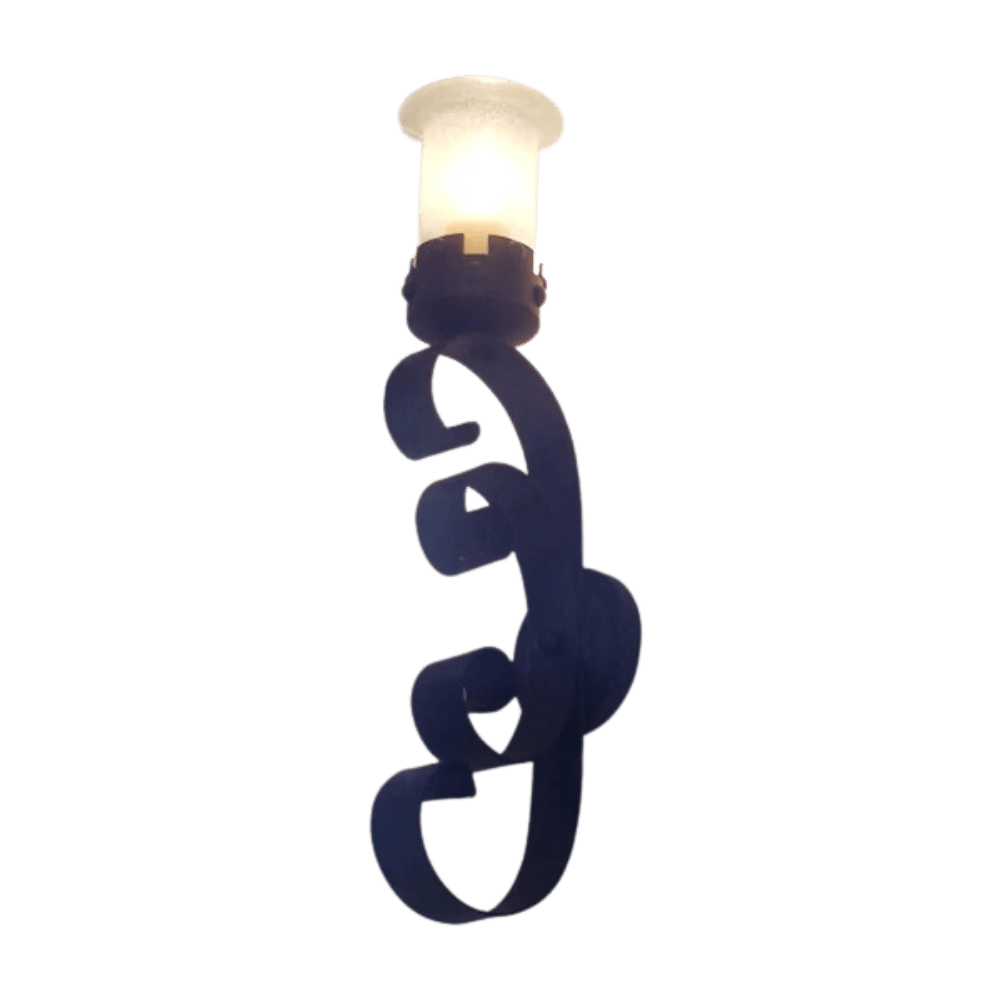 A decorative wall sconce featuring intricate wrought iron detailing. The design includes elegant curves and a frosted glass light fixture at the top, casting a warm glow. This piece adds classic charm to any space.
