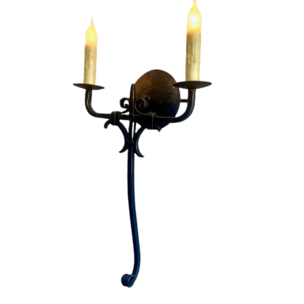 A decorative wrought iron sconce featuring two candle-style lights. The design incorporates elegant curves and intricate detailing, highlighted by a round centerpiece.