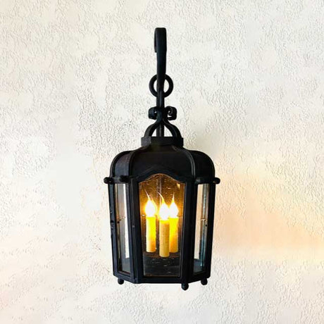 A beautifully crafted wrought iron pendant fixture featuring three candle-style bulbs inside a glass enclosure. The elegant design is complemented by intricate detailing and a sturdy hook for hanging, ideal for adding warmth and ambiance to any space.
