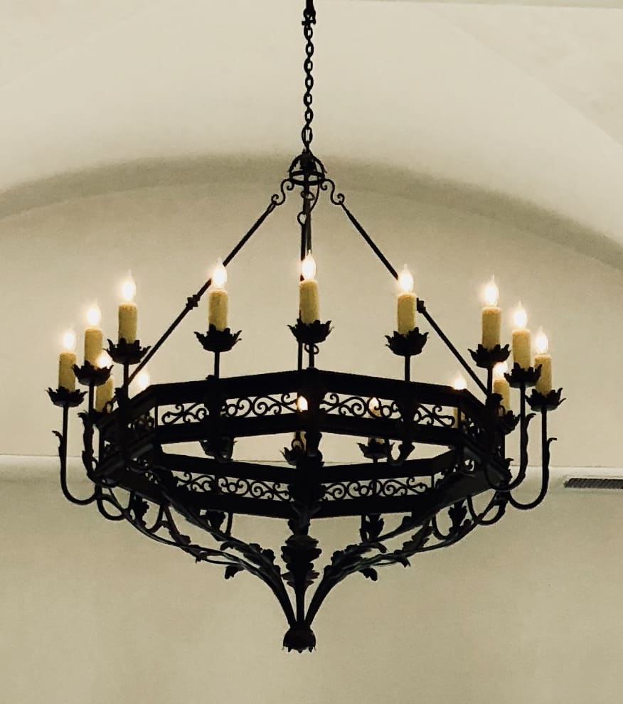 A striking wrought iron chandelier featuring intricate detailing and multiple candle-like lights, adding elegance to any space.