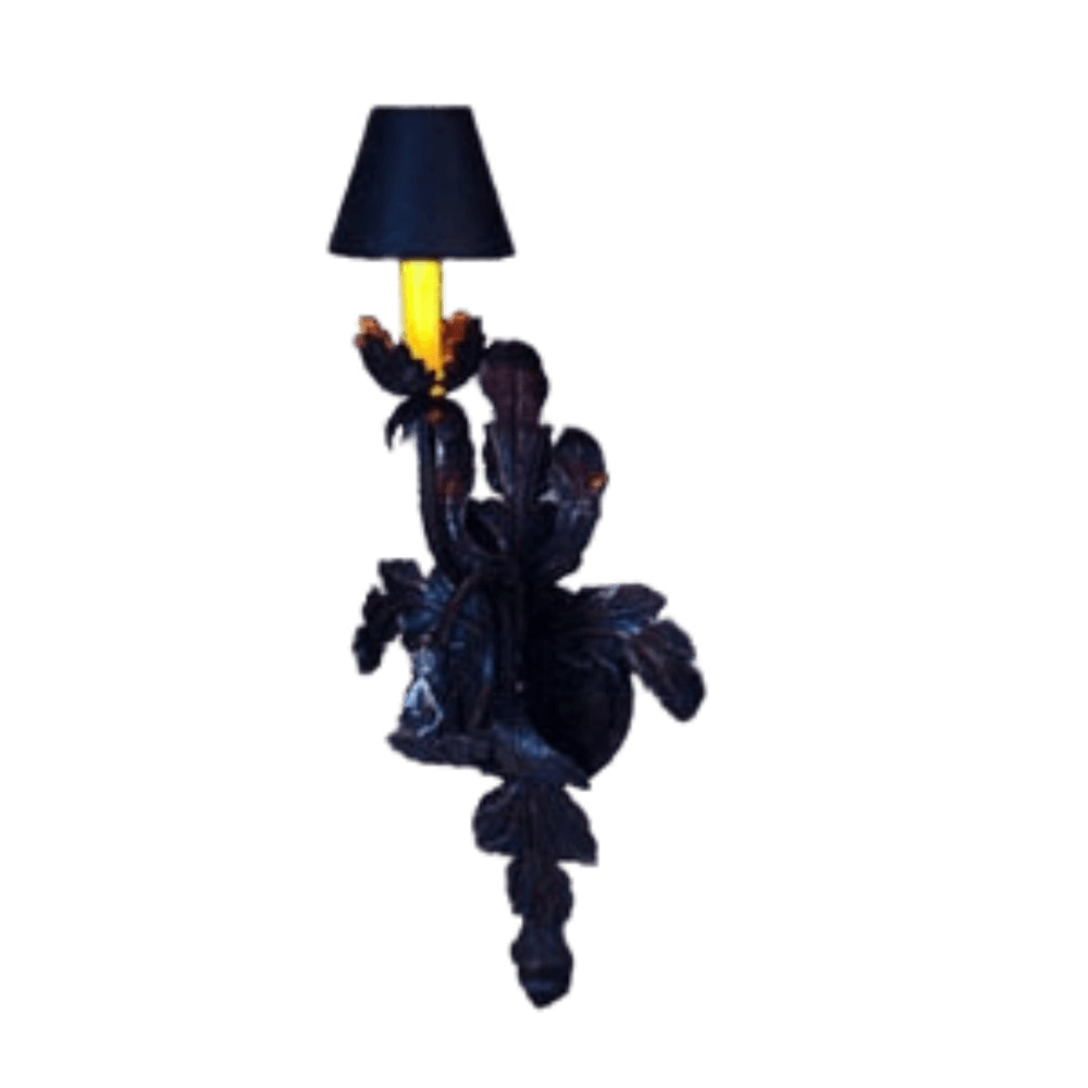 A decorative wall sconce featuring intricate wrought iron leaf motifs, crowned with a sleek black shade. The warm glow from the bulb creates an inviting ambiance, enhancing both traditional and contemporary decor styles.