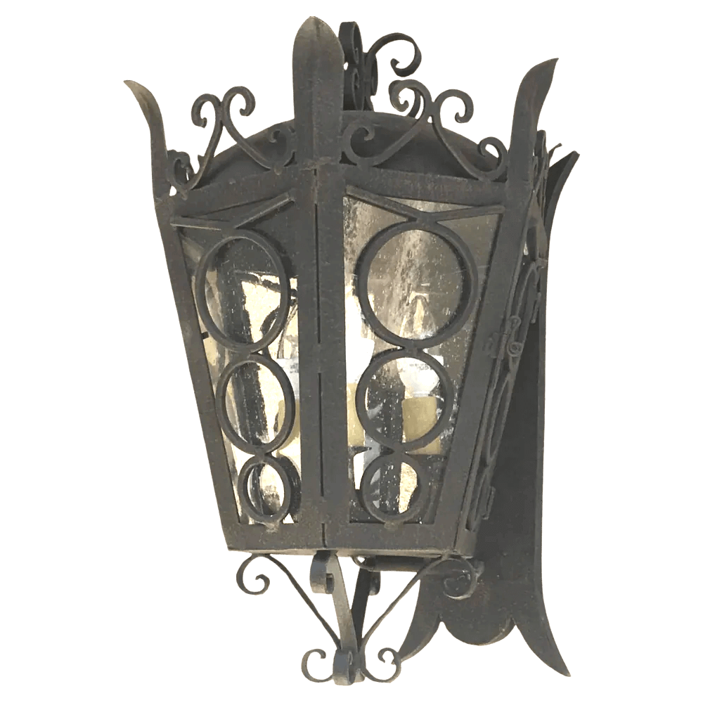 A decorative wrought iron sconce featuring an intricate design with circular cutouts and glass panels, showcasing soft, warm lighting inside.