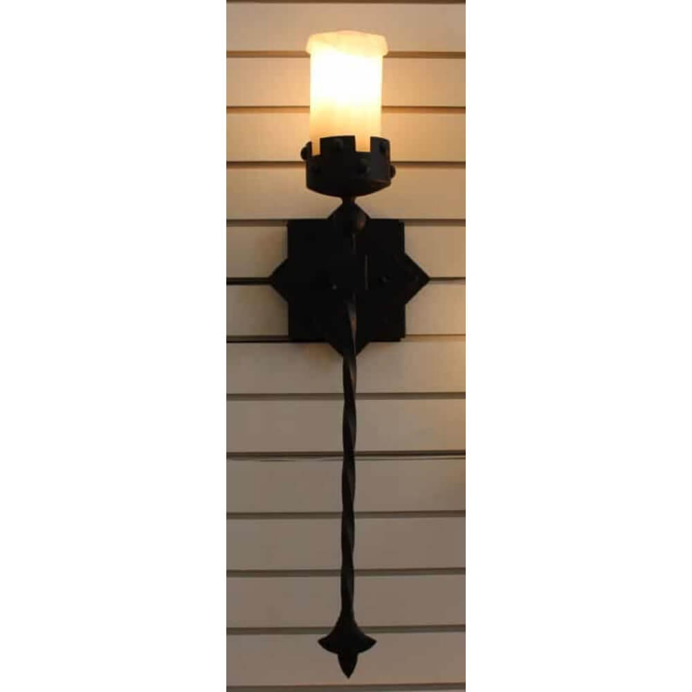 A decorative wall-mounted sconce featuring a twisted iron stem and a sculpted candle holder. The warm, glowing candle emits a soft light, enhancing the intricate design of the fixture. The black iron finish provides a rustic charm, perfect for adding character to any space.