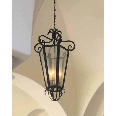 A decorative hanging fixture with intricate wrought iron detailing and a glass enclosure, illuminating the space with warm light.