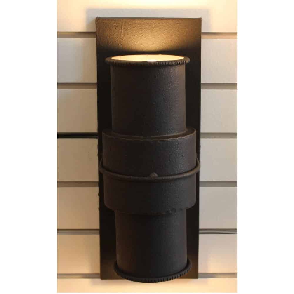 A striking wall sconce featuring a stacked design of cylindrical wrought iron forms. The fixture showcases a rich black finish, exuding a rustic elegance. Soft light emanates from the top, creating a warm ambiance perfect for various settings.