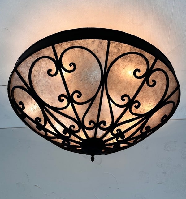 A beautifully designed ceiling fixture featuring ornate, swirling wrought iron elements and soft, warm lighting that enhances any space.