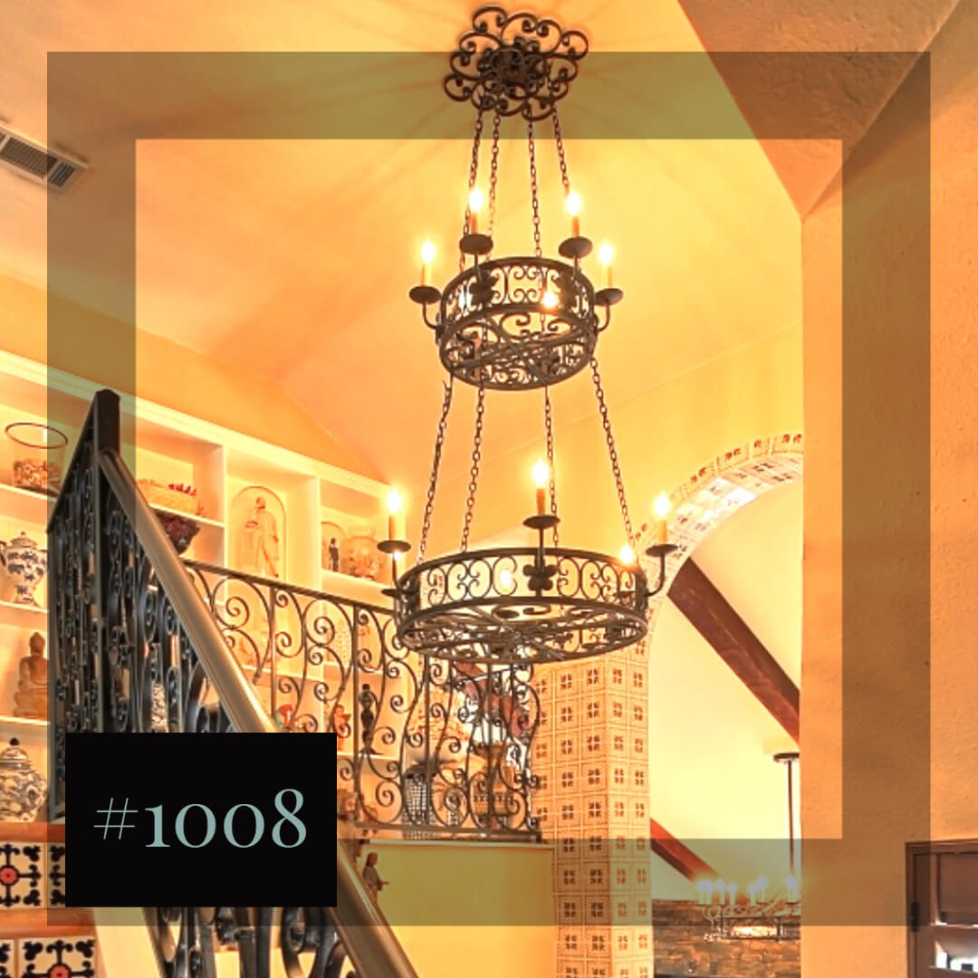 A stunning wrought iron chandelier featuring intricate curves and candle-like lights, suspended from a ceiling in a warm-toned interior. The design brings elegance and an artisanal touch to the space.