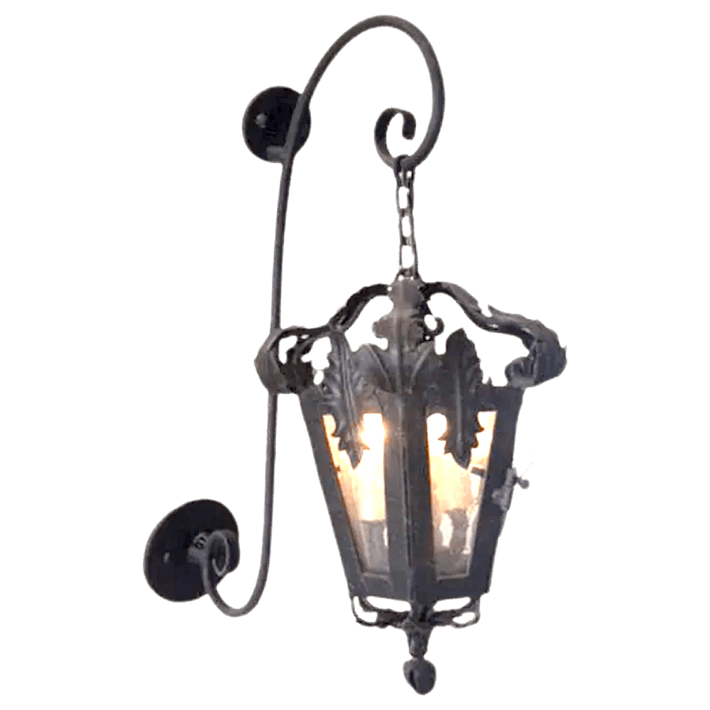 A decorative wrought iron sconce featuring an ornate design with intricate leaf motifs and a glass enclosure, softly illuminating the space within.