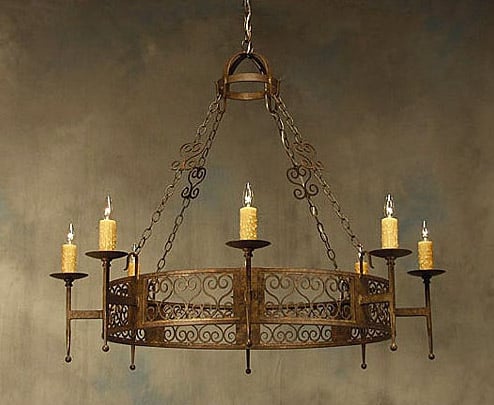 A beautifully crafted wrought iron chandelier featuring a circular design with intricate scrollwork. It holds six elegant candle-style lights with textured yellow shades, suspended by sturdy chains. The warm, rustic finish adds charm to any space.
