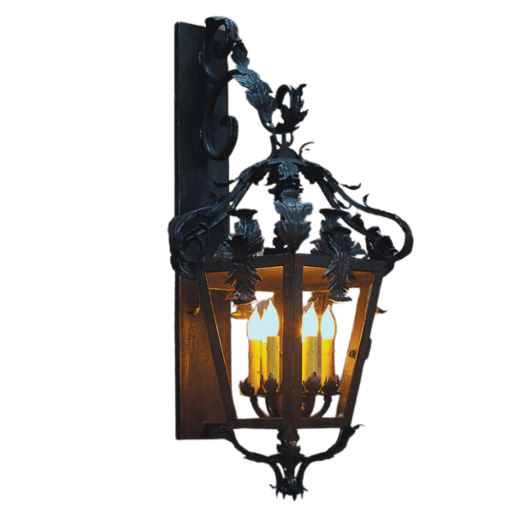 A beautifully crafted wall sconce featuring intricate wrought iron detailing and a warm glow from four candles. The design showcases elegant curves and floral motifs, enhancing any interior or exterior space with a charming rustic feel.