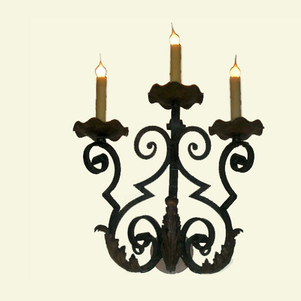 A decorative wrought iron chandelier featuring three candle-like lights. The design includes elegant swirling patterns and intricate detailing, providing a classic and artistic illumination that enhances any space.
