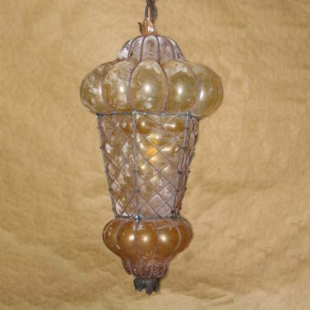 A beautifully crafted pendant light featuring a unique, rounded design with a wire framework. The fixture showcases a warm amber glow, highlighting its intricate glass elements and elegant curves, perfect for adding a charming touch to any space.