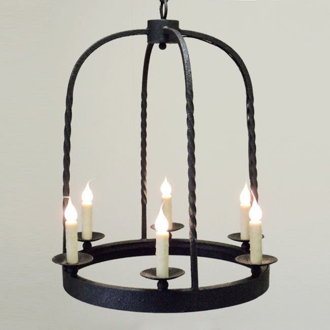 A handcrafted wrought iron chandelier featuring five candle-like lights, elegantly suspended by twisted rods, casting a warm and inviting glow.