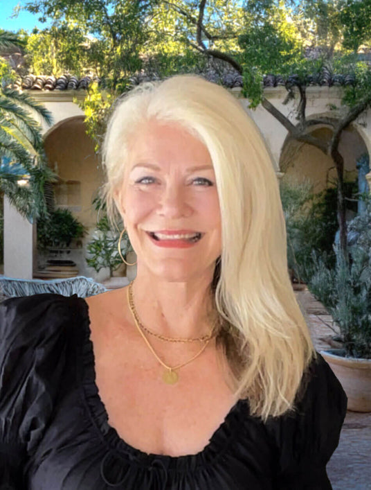 Kim Harper, the founder of Illuminaries standing in front of a Spanish-style villa.