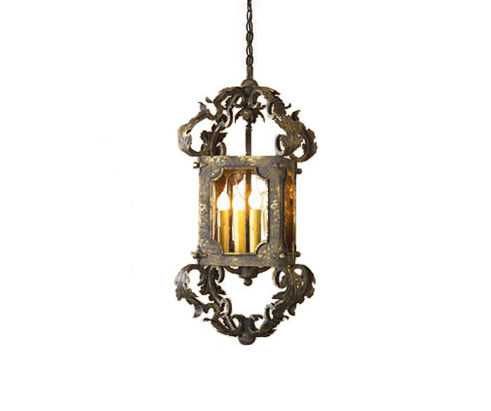 An ornate wrought iron pendant featuring intricate scrollwork and a rectangular frame, illuminating with warm light from multiple bulbs.