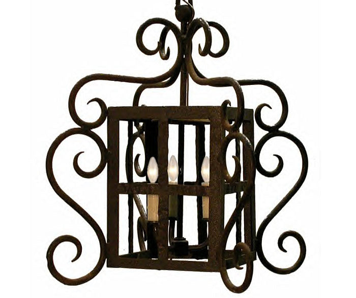 An ornate wrought iron pendant featuring intricate swirling designs and a square frame. Inside, four candle-like fixtures illuminate the space, creating an elegant ambiance.
