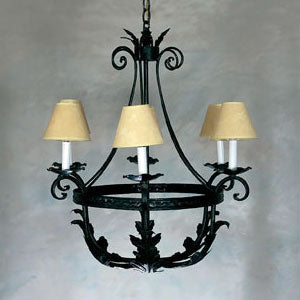 A decorative chandelier featuring a circular wrought iron frame adorned with intricate leaf designs. It houses three elegant cream-colored lampshades that gently diffuse light, adding warmth to any space. The design combines elegance and artistry, perfect for enhancing traditional or rustic interiors.