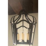 A beautifully crafted wrought iron pendant light featuring an ornate design. It has three candle-style bulbs with textured, cream-colored bases. The fixture's elegant curves and intricate detailing create a warm, inviting atmosphere, perfect for enhancing any space.