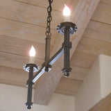 A two-light wrought iron chandelier featuring elegant, candle-like bulbs and a sleek, linear design. The fixture hangs from a chain against a wooden ceiling, adding sophistication to any space.