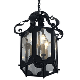 A beautifully crafted wrought iron pendant featuring intricate scrollwork and an octagonal design. The fixture showcases clear glass panels, illuminating the interior with soft light from candle-style bulbs.