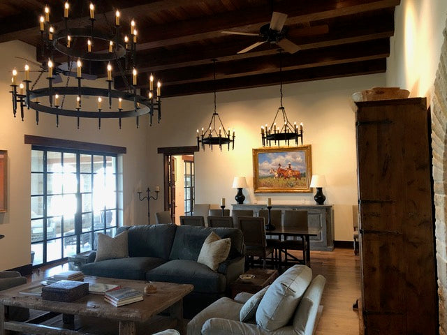 A large wrought iron chandelier featuring multiple candle-style lights. The design includes elegant arms and chains, creating a rustic yet refined ambiance.