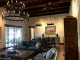 A large wrought iron chandelier featuring multiple candle-style lights. The design includes elegant arms and chains, creating a rustic yet refined ambiance.