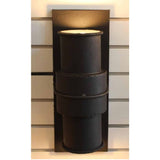 A striking wall sconce featuring a stacked design of cylindrical wrought iron forms. The fixture showcases a rich black finish, exuding a rustic elegance. Soft light emanates from the top, creating a warm ambiance perfect for various settings.