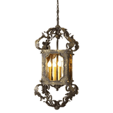 A beautifully crafted pendant light featuring intricate wrought iron detailing. The design includes a framed glass enclosure showcasing four warm bulbs, encircled by ornate scrollwork for a refined touch.
