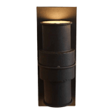 A stylish wrought iron wall sconce featuring a cylindrical design with textured surfaces and an elegant ring detail. The warm light casts a welcoming glow, enhancing any decor.