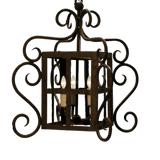This ornate pendant features intricate wrought iron design with elegant curves and scrollwork, housing four candle-like lights for a warm glow.