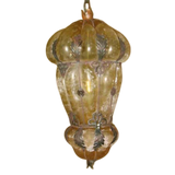 A beautifully crafted pendant light featuring a decorative, curved glass shade with intricate iron detailing. The warm hues and ornate design add elegance to any space, enhancing the ambiance with its unique charm.