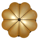 A round ceiling light fixture featuring a floral design with eight petal-like shapes, each in a warm, golden hue. The center is accented with a circular element, enhancing its elegant appearance, perfect for adding a touch of sophistication to any space.