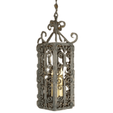 An intricately designed wrought iron pendant light featuring ornate scrollwork and a warm glow from its central bulb, ideal for adding elegance to any space.