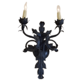Wrought iron wall sconce featuring two elegant candle holders shaped like flowers, adorned with intricate scrollwork and leafy details, creating a sophisticated and artistic lighting option.