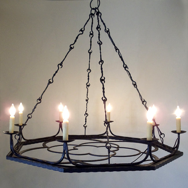 A striking wrought iron chandelier featuring an ornate design, suspended by elegant chains. It holds multiple candle-style lights, enhancing any room's warmth and ambiance.