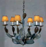 A unique wrought iron chandelier featuring an organic design with leaf-like elements. It has six warm-toned fabric shades, creating a cozy ambiance. The intricate details and rustic finish add character, making it a striking centerpiece for any room.