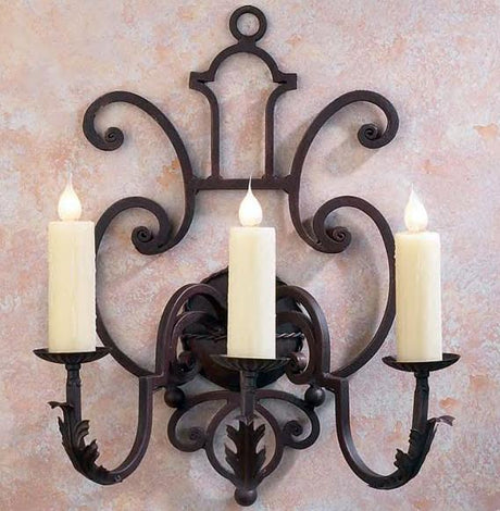 A decorative wall sconce featuring three elegantly curved arms and subtle floral accents, each holding a tall, creamy candle. The intricate wrought iron design combines artistry and functionality, perfect for adding warmth and sophistication to any room.