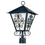 A decorative wrought iron sconce featuring a peaked roof and intricate scrollwork, with frosted glass panels illuminating softly.