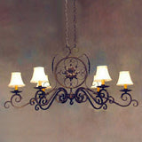 A decorative wrought iron chandelier featuring elegant curves and a central floral design. It includes five softly lit shades, adding a warm ambiance to the space. Perfect for enhancing any room with a classic touch.
